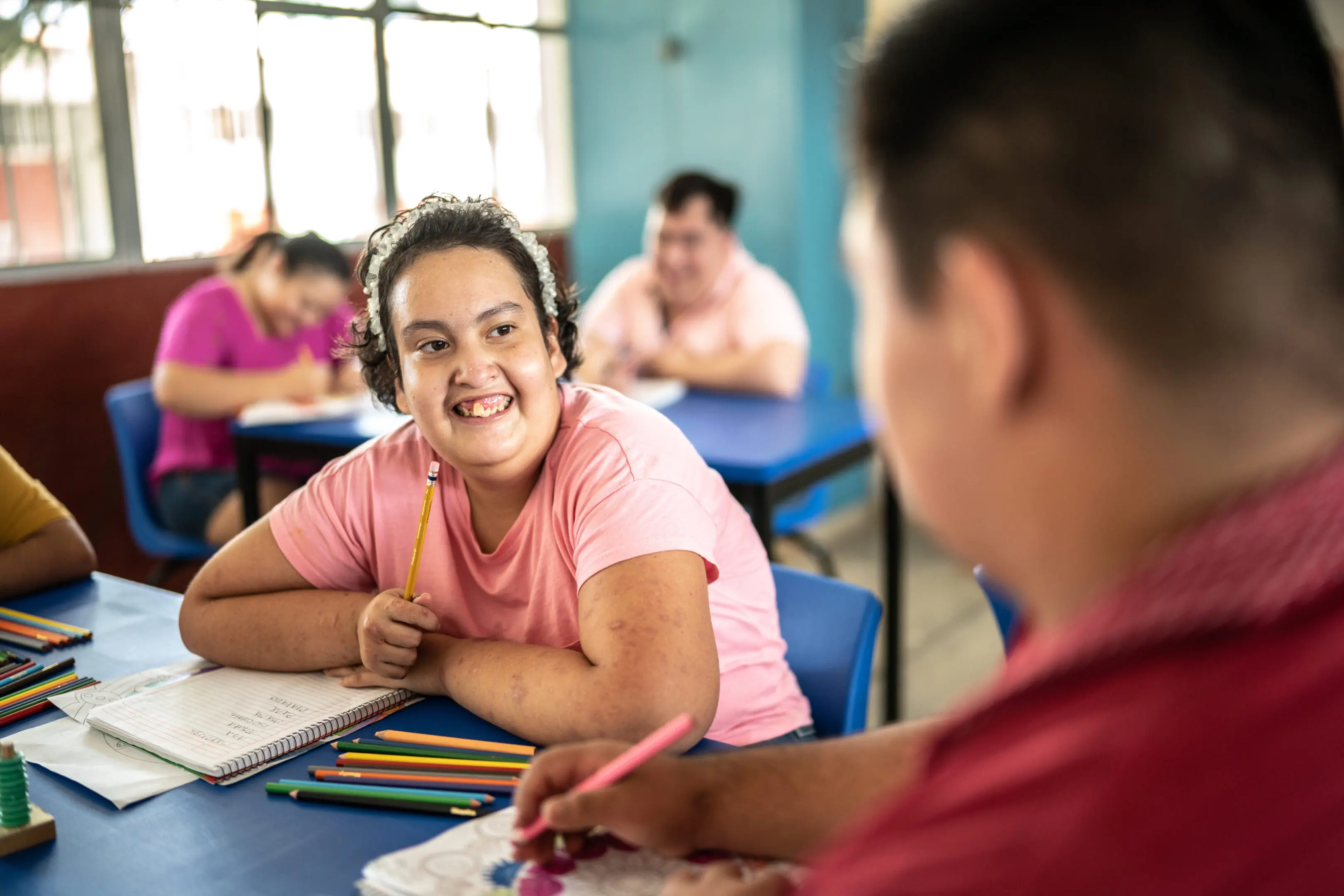 Two students happily interacting while doing schoolwork in a classroom.