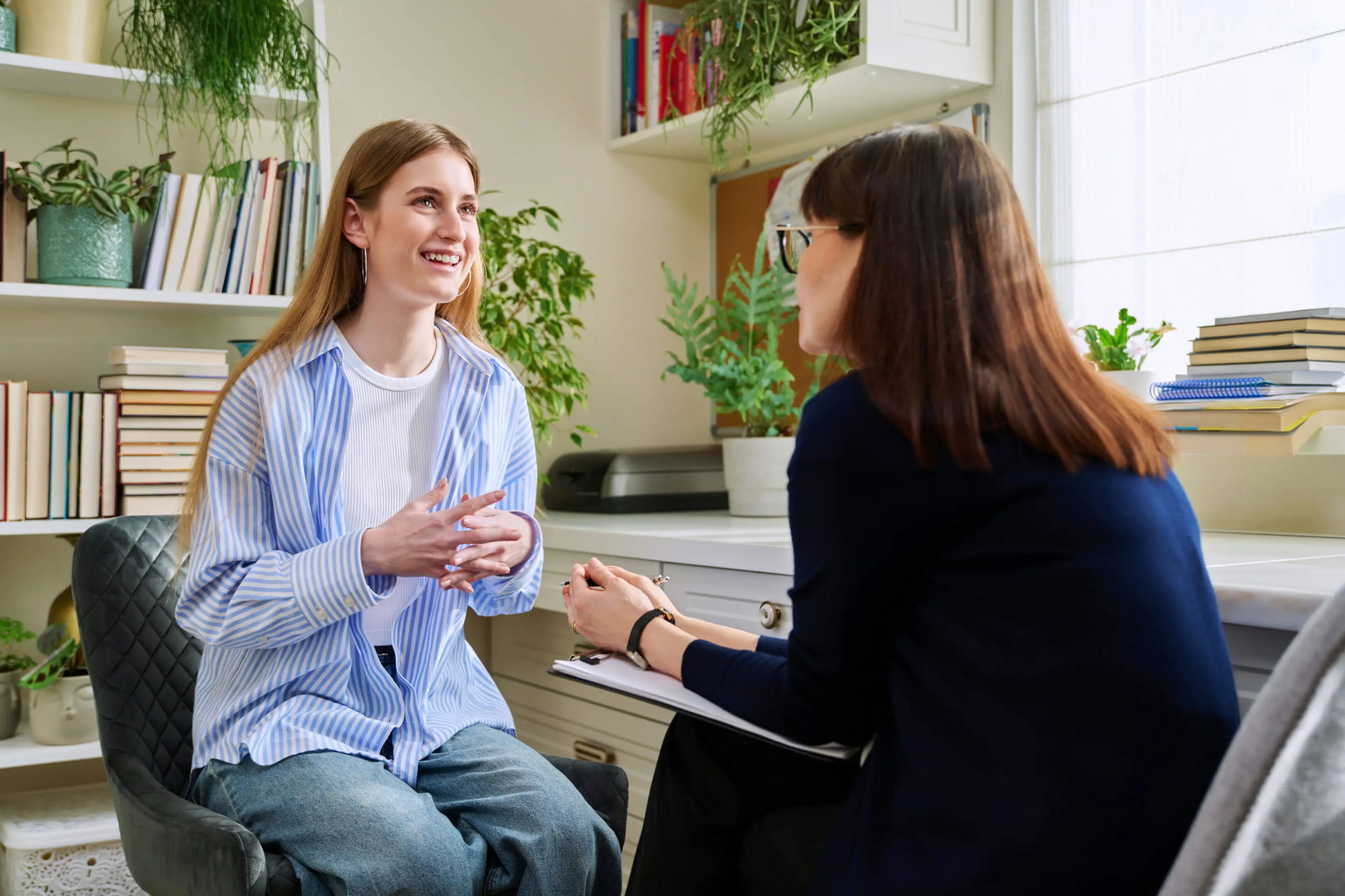 Two women having a friendly conversation in a bright room.