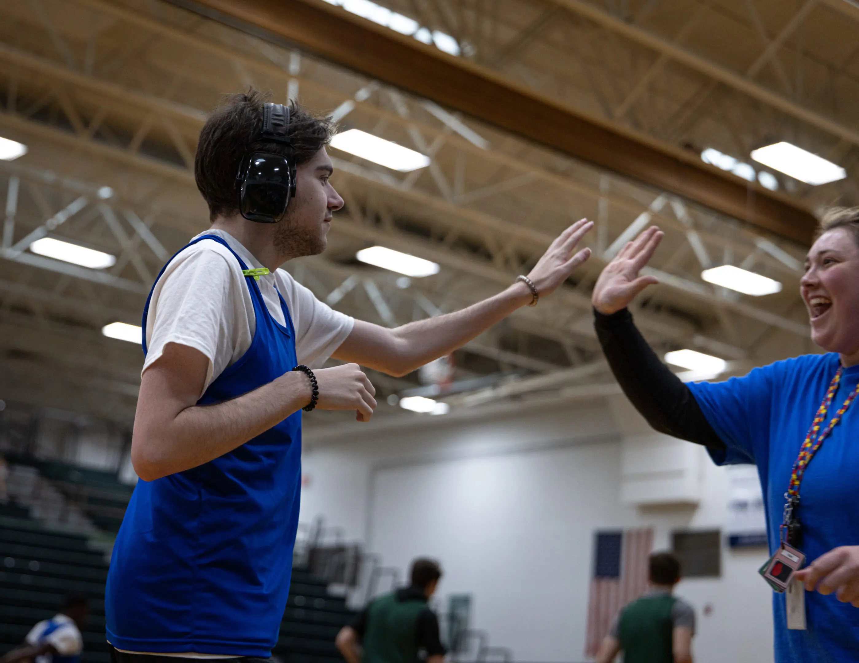 Two basketball players exchanging a high five during a game indoors.