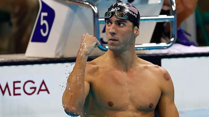 Swimmer celebrating a victory with a fist pump at the poolside.
