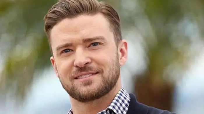Portrait of a smiling man in a checkered shirt and blazer.