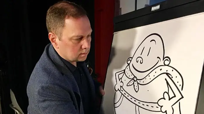 Man drawing a cartoon character on a large paper pad.
