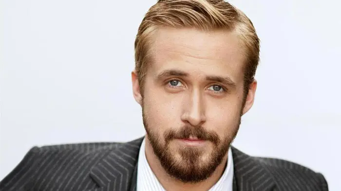 Close-up of a man with light hair and beard wearing a striped suit jacket.