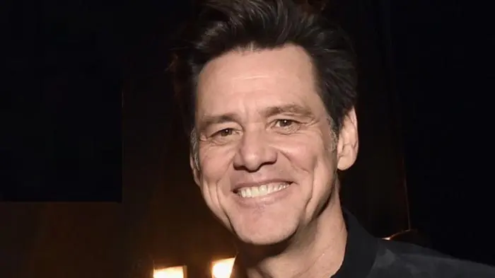 Portrait of a smiling man with dark hair in a dark setting.