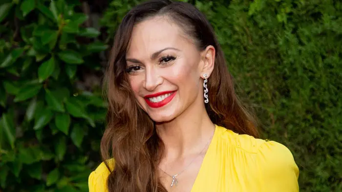 Smiling woman with red lipstick and yellow blouse.