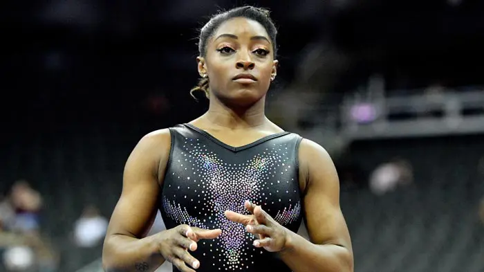 Focused gymnast preparing for a routine in a sparkling leotard.