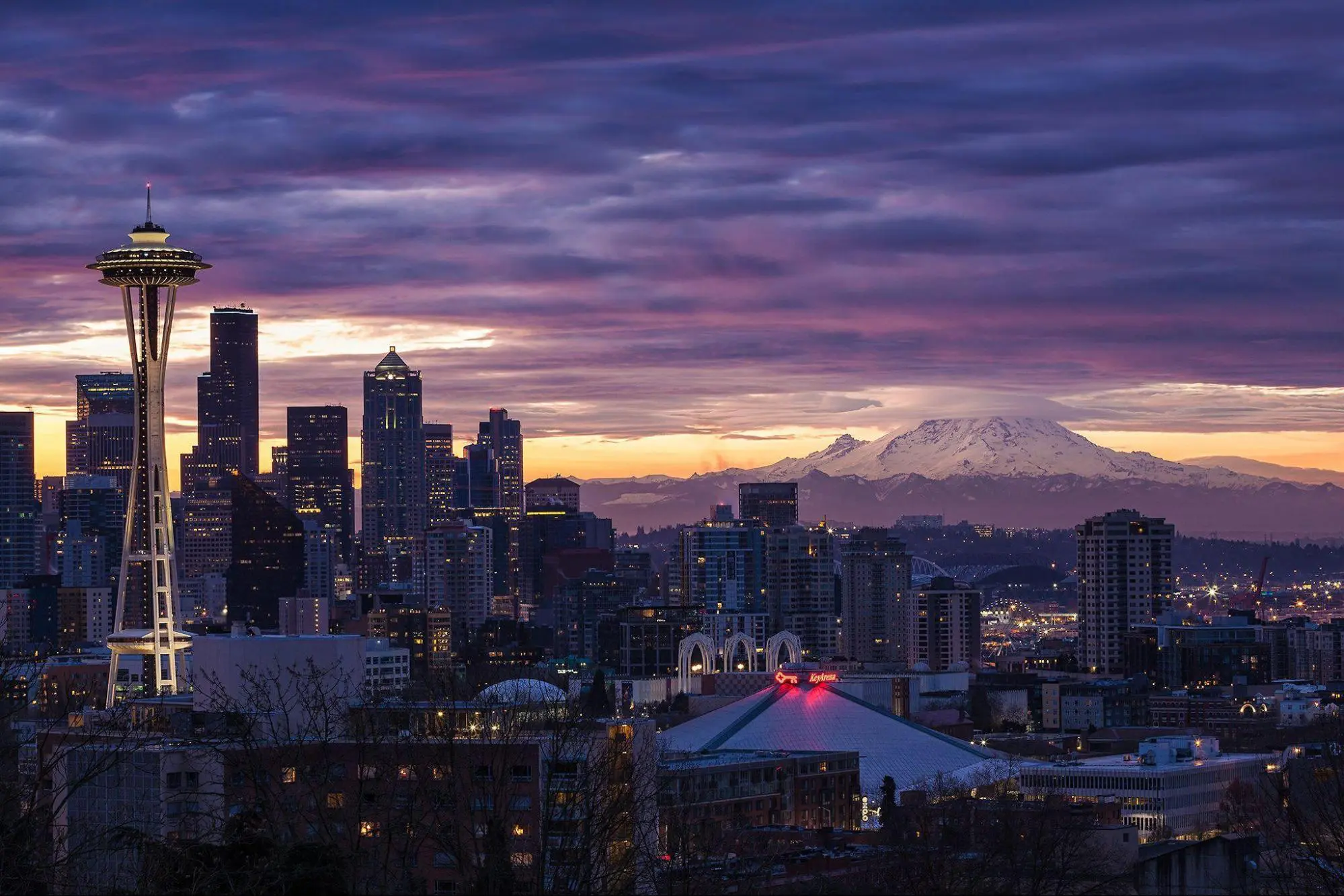 City skyline at sunset with vibrant purple and orange skies.