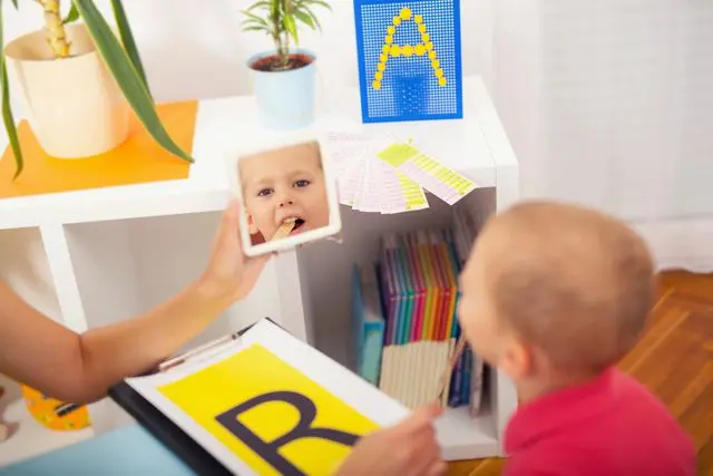 A child learning letters with flashcards and an adult's help.
