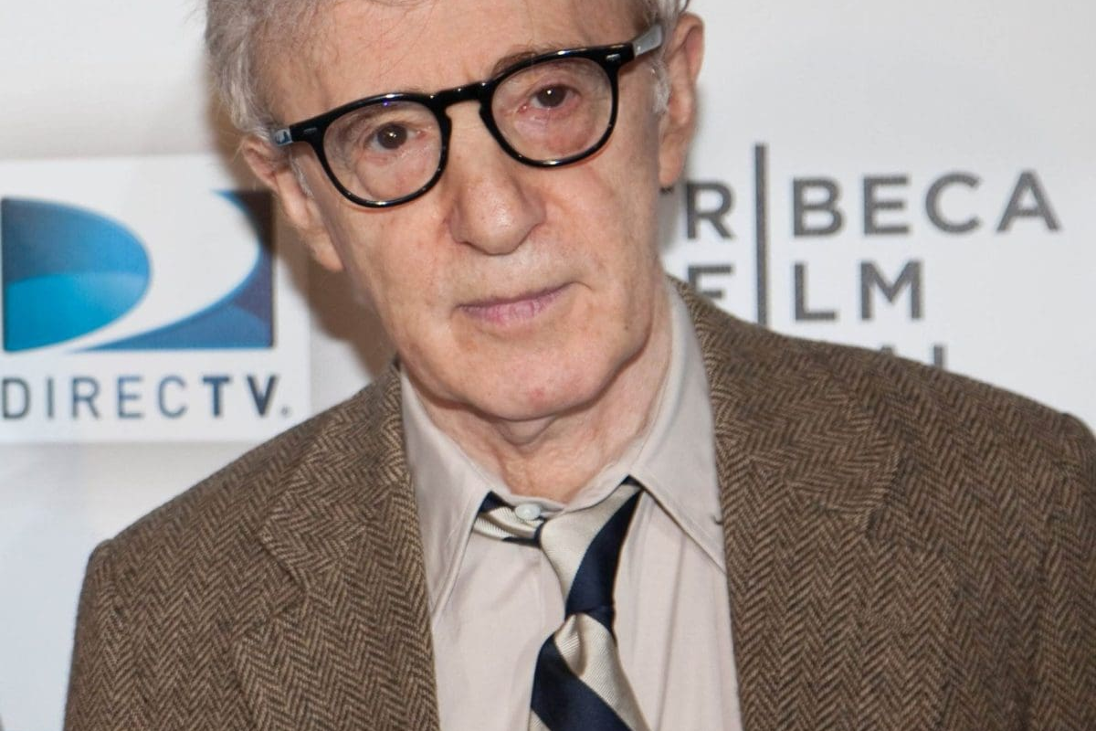 Elderly man with glasses dressed in a suit and tie at an event.
